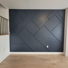 an empty room with wood flooring and blue painted wall in the background is a staircase