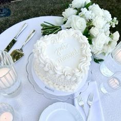 there is a wedding cake on the table with white flowers and silverware around it