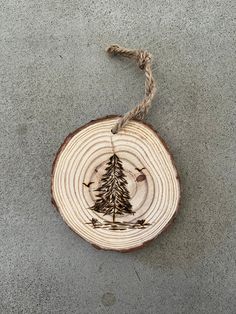 a piece of wood with a pine tree on it hanging from a rope in front of a cement wall