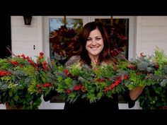 a woman is holding two christmas wreaths in front of her face and smiling at the camera