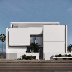 a large white building sitting on the side of a road with palm trees in front of it