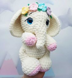 a crocheted elephant with flowers on it's head sitting in someones hand