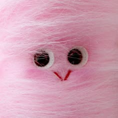 a pink stuffed animal with eyes and hair