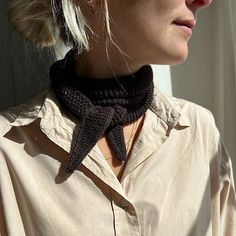 a woman with blonde hair wearing a black crocheted neck tie and beige shirt