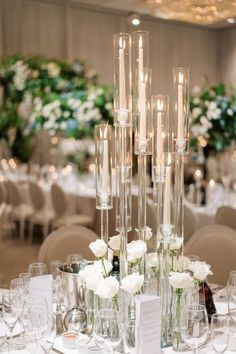 the centerpieces are filled with white flowers and candles in tall glass vases