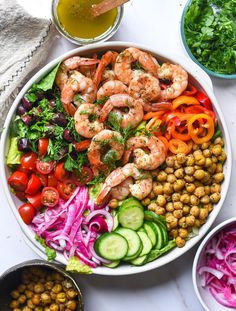 a salad with shrimp, carrots, cucumber, red onion, and lettuce