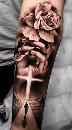 a cross and rose tattoo on the arm with an image of a person holding a flower