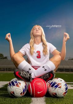 a woman is sitting on the ground with soccer balls