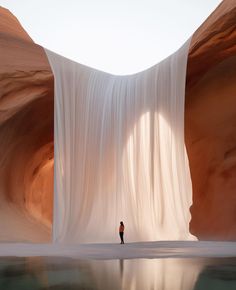 a person standing in the middle of a desert area with water and sand dunes behind them