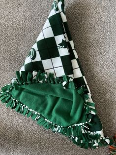 a green and white blanket laying on top of a carpeted floor next to a black and white checkered towel