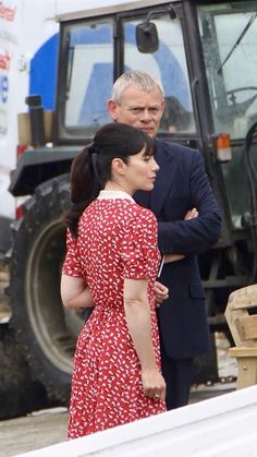 two people standing next to each other in front of a tractor