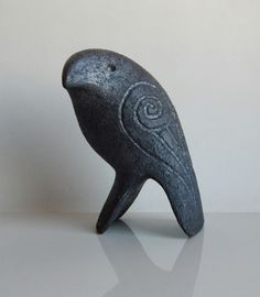 a black bird statue sitting on top of a table next to a white wall and floor