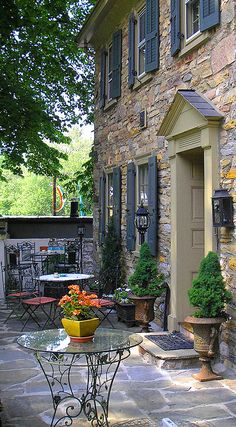 an outdoor patio with tables, chairs and potted plants on the side of it