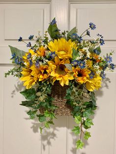 a basket filled with sunflowers and greenery hanging from a door handle on a wall