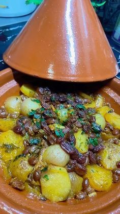 a plate topped with potatoes and nuts next to a brown cone shaped dish on top of a table