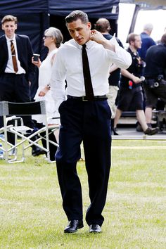 a man is walking in the grass with his hand on his ear and other people behind him