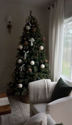 a living room with a christmas tree in the corner and pillows on the couches