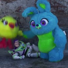 two stuffed animals that are sitting next to each other on the ground and one has a toy in it's hand