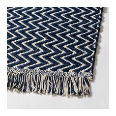 a blue and white rug with fringes on the bottom, sitting on top of a table