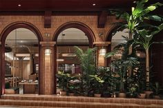 the interior of a restaurant with potted plants in front of large arched doorways