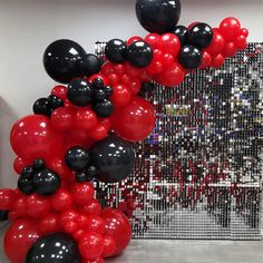 red and black balloons are in the shape of an arch on display at a museum