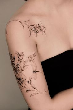 a woman with a flower tattoo on her arm and shoulder is holding a cell phone