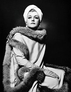 a black and white photo of a woman wearing a fur stole with her hands on her hips