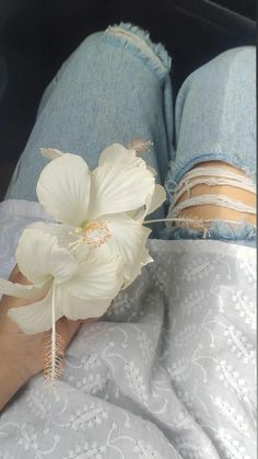 a person laying in bed with their feet up on the pillow and holding a flower