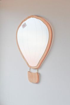 a mirror mounted to the side of a wall with a wooden frame and light bulb