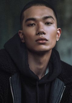 a young man wearing a black jacket and looking at the camera with an intense look on his face