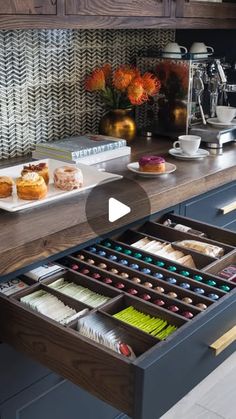 an open drawer in a kitchen filled with cakes and cupcakes on top of a counter