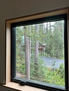 a window with a view of a road through the woods and trees in front of it