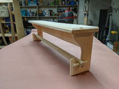 a wooden bench sitting on top of a pink surface in a room filled with tools