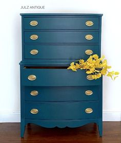 a blue dresser with yellow flowers sitting on it's top and the bottom drawers