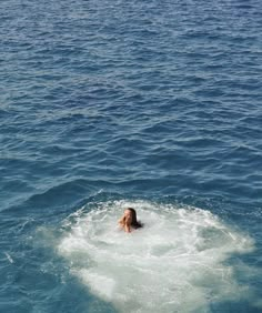 a woman is swimming in the ocean with her head above the water's surface