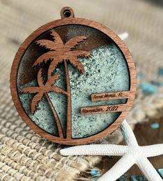 a wooden ornament with a palm tree and starfish on the beach next to it