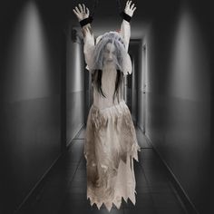 a woman dressed as a ghost walking down a hallway with her hands in the air