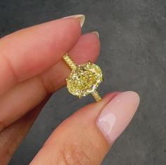 a woman's hand holding a yellow diamond ring