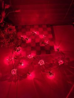 red lights are shining on the floor in front of a checkerboard pattern and potted plants