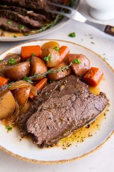 a plate with meat, potatoes and carrots on it