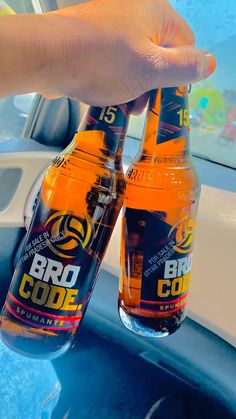 two bottles of beer sitting on top of a blue table next to a person's hand