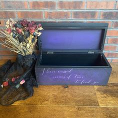 a purple box with flowers in it sitting on a wooden floor next to a brick wall