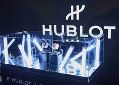 the hublot logo is lit up in front of a display case with watches inside