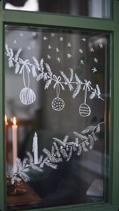 a frosted glass window with christmas decorations on it and a lit candle in the background