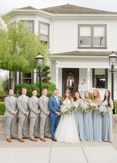 a group of people standing in front of a white house with flowers on the bouquets