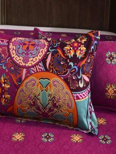 a bed topped with two pillows covered in colorful designs