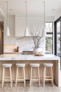 a kitchen with marble counter tops and white stools next to an island in the middle