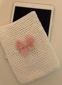 an ipad with a crochet bow on it next to a knitted cloth