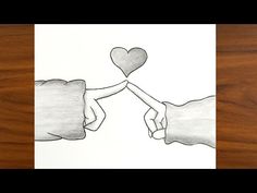 two hands holding each other over a piece of paper with the shape of a heart