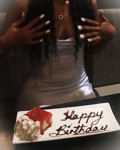 a woman sitting in front of a birthday cake with the words happy birthday written on it